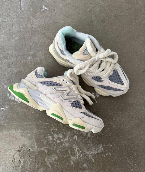 סניקרס ניו באלאנס במראה וינטג' עם סוליה ירוקה ורקעים אפורים, מונחות על רצפת בטון