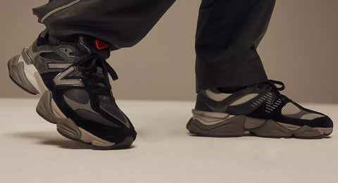 נעלי ניו באלאנס 9060 שחור אפור מוצגות על רצפה בהירה עם מכנס שחור